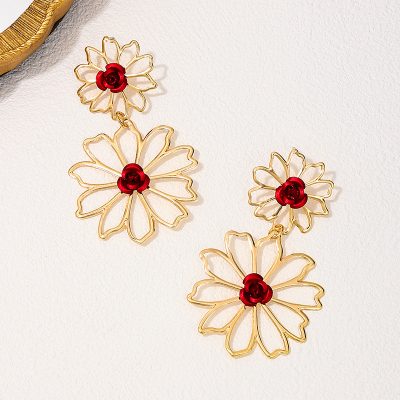 Gold flower-shaped earrings with red rose accents, perfect for elegant jewelry collections and statement accessories.