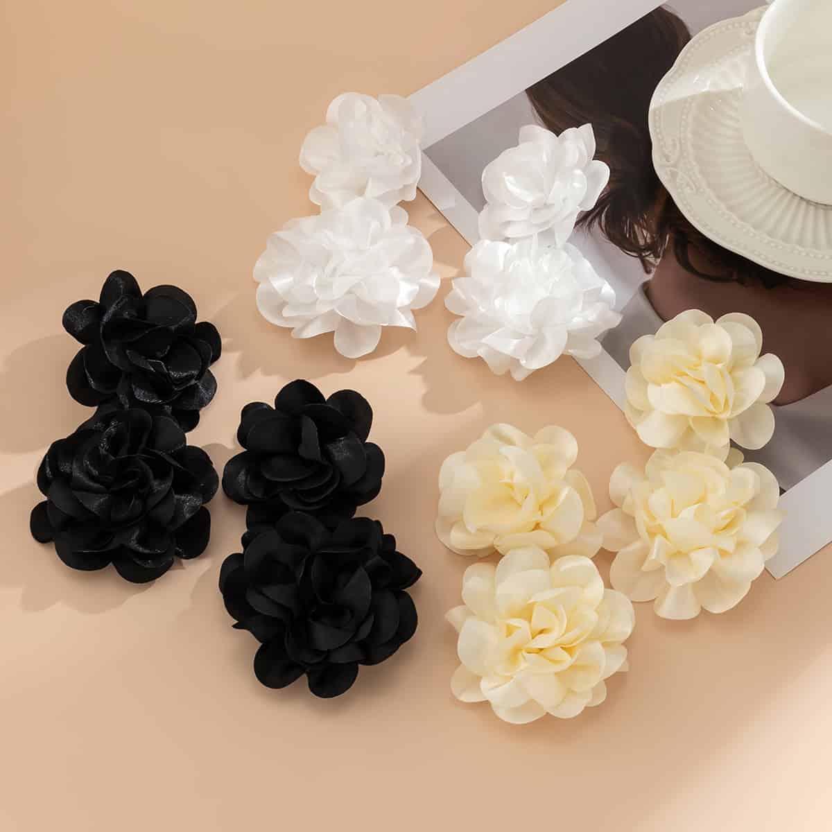 Silk flower hair accessories in black, white, and cream colors, displayed on a beige background; perfect for stylish hair decoration and fashion.