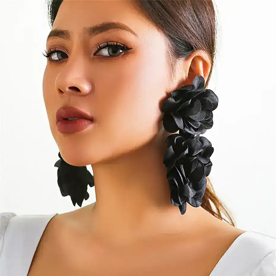 Elegant woman with large black floral earrings, showcasing trendy and fashionable jewelry for women. Perfect accessory for special occasions and stylish outfits.