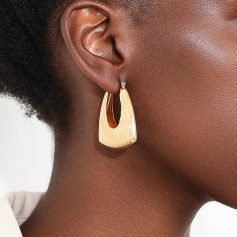 Shiny gold statement earring on a woman's ear, close-up, stylish jewelry accessory, perfect for fashion and beauty enhancements.