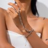 Shiny silver chain jewelry worn on woman’s wrist and fingers, close-up shot.
