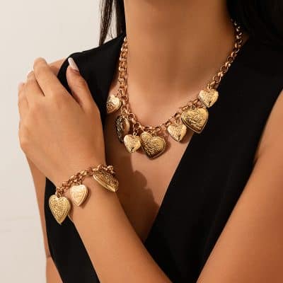 Shiny gold heart-shaped jewelry set including necklace and matching bracelet, featuring engraved floral and swirl designs, ideal for elegant fashion and gift-giving.