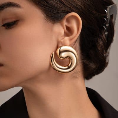 Luxurious gold spiral statement earring styled for elegant fashion, perfect for accessorizing and adding sophistication to your look.