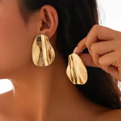Gold metallic statement earrings with reflective surface, trendy jewelry, fashion accessories for women.