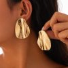 Shiny gold abstract earrings worn by a model, perfect for elegant accessories and statement jewelry.