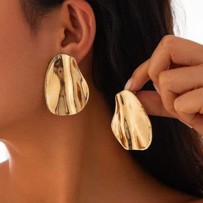 Shiny gold abstract earrings worn by a model, perfect for elegant accessories and statement jewelry.