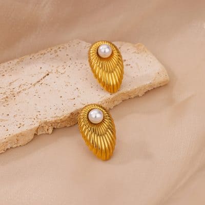 Elegant gold and pearl earrings displayed on a beige textured surface, perfect for enhancing your style with luxurious jewelry. Ideal for special occasions or everyday elegance from Monalisa Store.