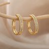 Delicate gold hoop earrings adorned with sparkling cubic zirconia stones, perfect for enhancing your jewelry collection and elevating your elegant or casual look.