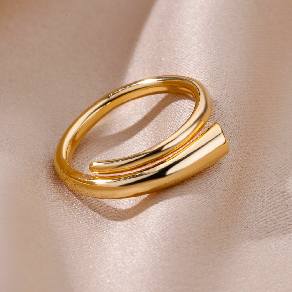 Shiny gold and silver modern minimalist ring for stylish jewelry accessories on soft satin fabric background.