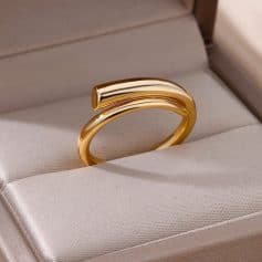 Shiny gold ring with curved bar design displayed in a jewelry box.
