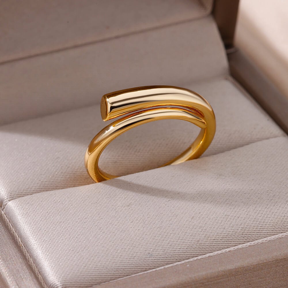 Shiny gold ring with curved bar design displayed in a jewelry box.