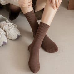 Comfy brown ribbed knee-high socks on a person's legs, with casual white sneakers nearby, showcasing fashionable eyewear accessories at Monalisa Store for stylish eye care and optical needs.