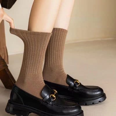 Comfy brown knee-high socks with loafers, stylish hosiery fashion, casual footwear, trendy casual shoes, comfortable knee-high stockings, fashionable sock and shoe combo, modern casual wear, sleek black loafers with gold accents, everyday fashion footwear, comfortable and stylish footwear for men and women.