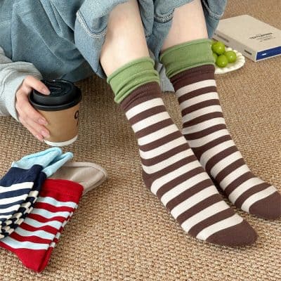 Comfy striped socks on woman's legs, cozy casual style with colorful socks for women and men, playful fashion accessory, indoor lounge setting.