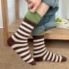 Comfy striped socks on a person’s feet, cozy indoor footwear, perfect for lounging or winter warmth.