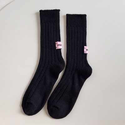 Comfortable black ribbed socks with pink brand labels, perfect for everyday wear and fashion statements. Ideal for casual, athletic, or stylish outfits.