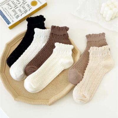 Comfy cable-knit ankle socks in neutral tones displayed on a decorative tray, perfect for everyday wear and fashion accessories.