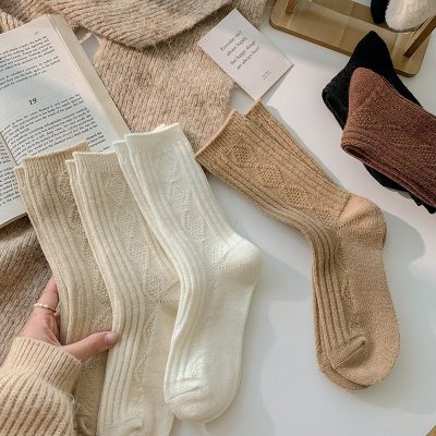 Soft neutral-colored knit socks displayed on a clean white surface, featuring various shades including cream, beige, and brown, with cozy textures and stylish patterns perfect for fall and winter wear.