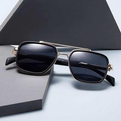 Sunglasses with black lenses and metal frame on gray and black background.
