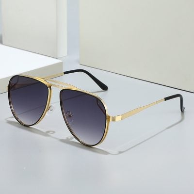 Fashionable gold-rimmed sunglasses with dark gradient lenses, perfect for stylish eye protection and vision correction, displayed on a sleek minimalistic surface.