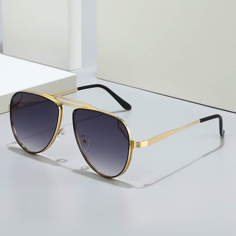 Fashionable gold-rimmed sunglasses with dark gradient lenses, perfect for stylish eye protection and vision correction, displayed on a sleek minimalistic surface.