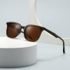 Sunglasses with brown tinted lenses on a white cylindrical platform, modern and stylish eyewear for sun protection.
