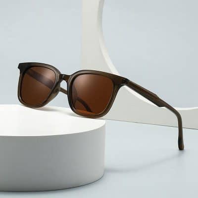 Sunglasses with brown tinted lenses on a white cylindrical platform, modern and stylish eyewear for sun protection.