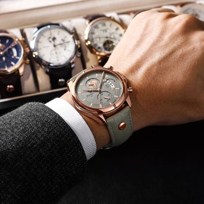 Shiny rose gold wristwatch with chronograph features, beige leather strap, and multiple watch displays, showcased on a person's wrist amid a collection of luxury watches at Monalisa Store.
