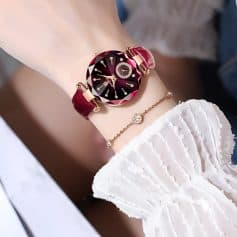 Luxurious women's wristwatch featuring a deep red, faceted gemstone-inspired dial with diamond accents, paired with elegant jewelry; perfect for stylish fashion and luxury accessories.