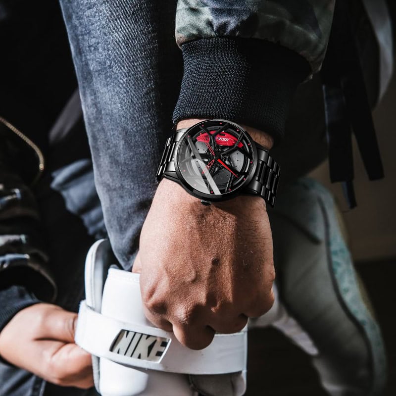 Black sporty wristwatch with red accents on a man's wrist, stylishly layered with casual streetwear accessories including a RFID Nike wristband, emphasizing modern men's fashion and watch style.