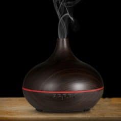 Essential oil diffuser with warm wood grain finish, remote control, and adjustable timing settings, enhances home ambiance and air quality. Ideal for relaxation and wellness routines.