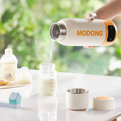Stainless steel insulated milk frothing pitcher pouring milk into baby bottle at Monalisa Store in eco-friendly kitchen setting.
