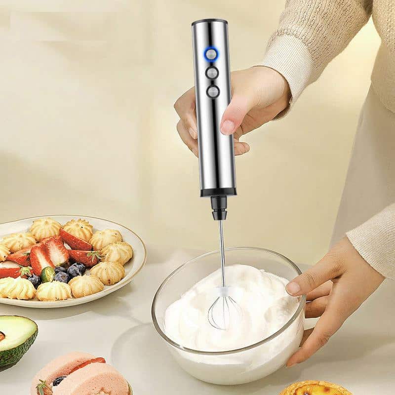 Whisking handheld immersion blender for kitchen use in glass bowl for cooking and baking purposes.