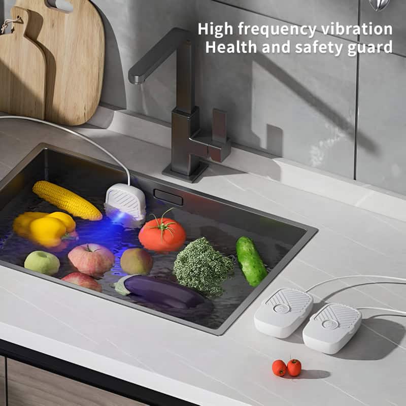 Fresh vegetables submerged in a kitchen sink with high frequency vibration health and safety guard for cleaning and detox.