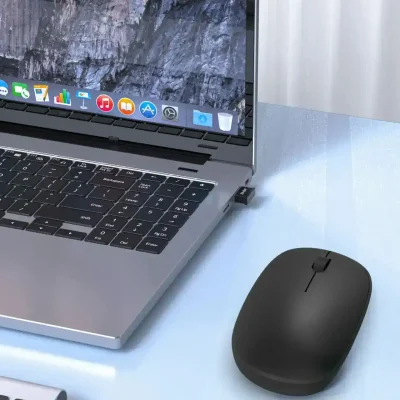 Laptop with macOS display, wireless mouse, and office supplies at Monalisa Store for optical and eyewear shopping.