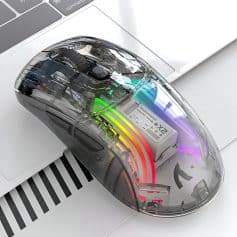 Computer mouse with transparent casing showing internal components, rainbow LED lighting, next to a white keyboard on a sleek workspace, highlighting modern computer accessories for enhanced productivity and style.