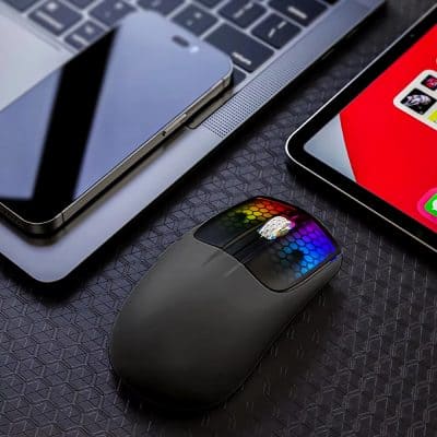 Wireless computer mouse with RGB lighting on a textured desk surface.