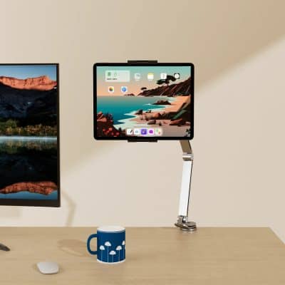 Laptop and tablet mounted on adjustable stand with the tablet showing a scenic beach landscape, ideal for tech workspace setup and digital productivity.