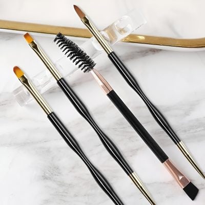 Precision makeup brushes and eyelash spoolie on marble surface for beauty and cosmetics. Perfect tools for professional makeup application and eyelash extension setups.