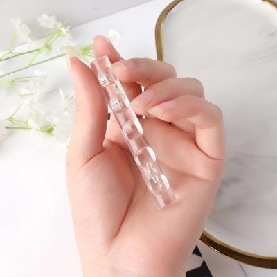 Aperture Hand Holding Glass Ampoule for Medical or Skincare Treatment, close-up of transparent medicine or cosmetic container.