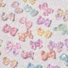 Colorful iridescent bow-shaped charms on textured white background, ideal for nail art, jewelry making, and craft supplies. Trending accessories for personalized, stylish DIY projects.