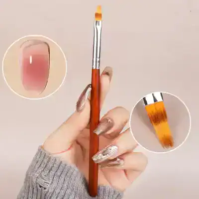 Bright pink nail polish with a gold accent on long, acrylic nails held by a hand with a manicure, featuring a small paintbrush, ideal for nail art, fashion, and beauty enthusiasts.