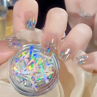 Shiny holographic nail art with glitter and rhinestones on natural nails, perfect for glamorous and stylish looks at Monalisa Store.