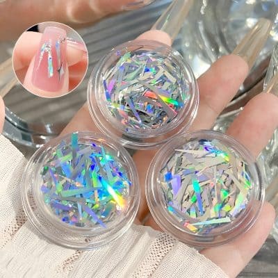 Shimmering holographic nail art glitter in clear containers, ideal for enhancing manicure designs with a sparkling, rainbow effect. Perfect for nail embellishments and beauty salons.