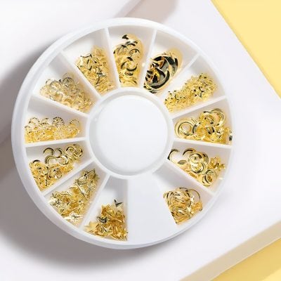 Shiny gold nail art embellishments in a round plastic organizing box, perfect for professional or DIY manicure and pedicure decoration, available at Monalisa Store.