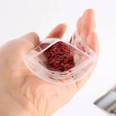 Red glitter gel in a small transparent container, held in hand.