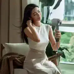 Gentlewoman using a modern hairdryer in a bright, stylish interior - promoting Monalisa Store's premium beauty and skincare products for radiant skin and hair care.