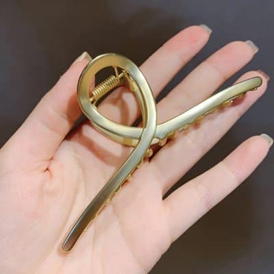 Golden hair clip with elegant scrolling design, perfect for adding a stylish touch to any hairstyle. High-quality accessory available at Monalisa Medical Store for women's fashion and hair ornament needs.