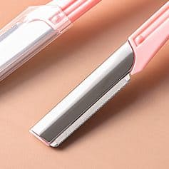 Shaving razor with a pink handle and protective cover, close-up view.