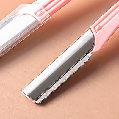 Shaving razor with a pink handle and protective cover, close-up view.